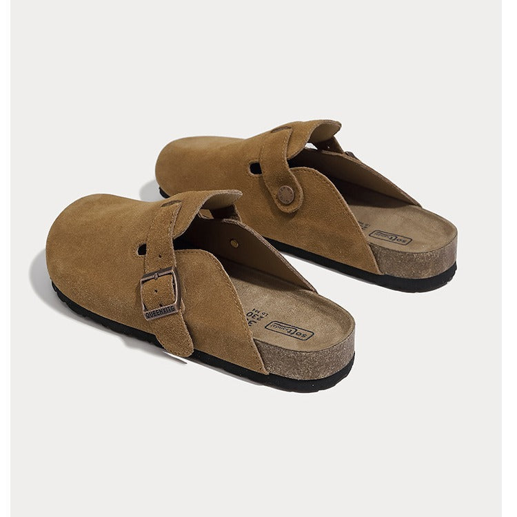 A pair of tan suede clogs birkenstock style with adjustable buckle straps and cork-look midsoles, photographed on a light gray background.