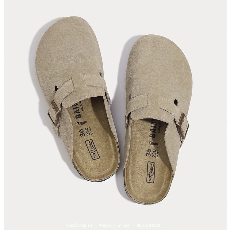 A pair of taupe suede clogs with adjustable buckle straps, shown from a top-down view on a light gray background.